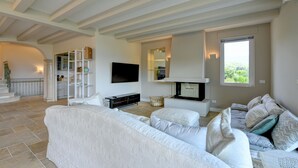 Una sala de estar moderna con un sofá blanco, un televisor de pantalla plana y una chimenea.