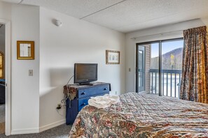 A hotel room with a bed, a dresser, a television, and a large window with a view of the outdoors. - Pico D305 condo ski on/off The best family mountain with access to the Pico Fitness Center (Killington)