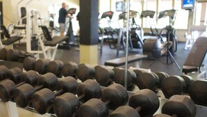 Ein Fitnessstudio mit Reihen von Kurzhanteln, Laufbändern und Trainingsgeräten.