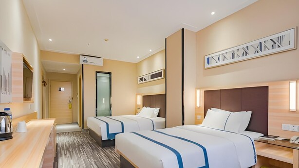 A hotel room with two beds, a desk, a coffee machine, and a bathroom door. - City Comfort Inn (Guangzhou)