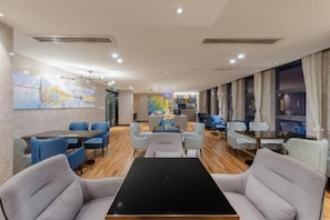 A hotel lobby with a seating area, a reception desk, and artwork on the walls. - Echarm Hotel Guangzhou Dayuan Time Plaza (Guangzhou)