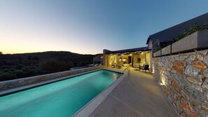 A modern villa with a swimming pool, stone walls, and a patio area with outdoor seating. - DAELIA VILLAS II of 3 Luxury Villas, private pool, in an enclosed olive grove (Plomari Lesvos)