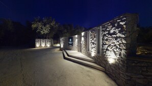 Een stenen muur met verlichte borden, een geplaveid pad en een donkere hemel.