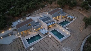 Een moderne villa met meerdere zwembaden, buitenzitplaatsen en een gevel van natuursteen.