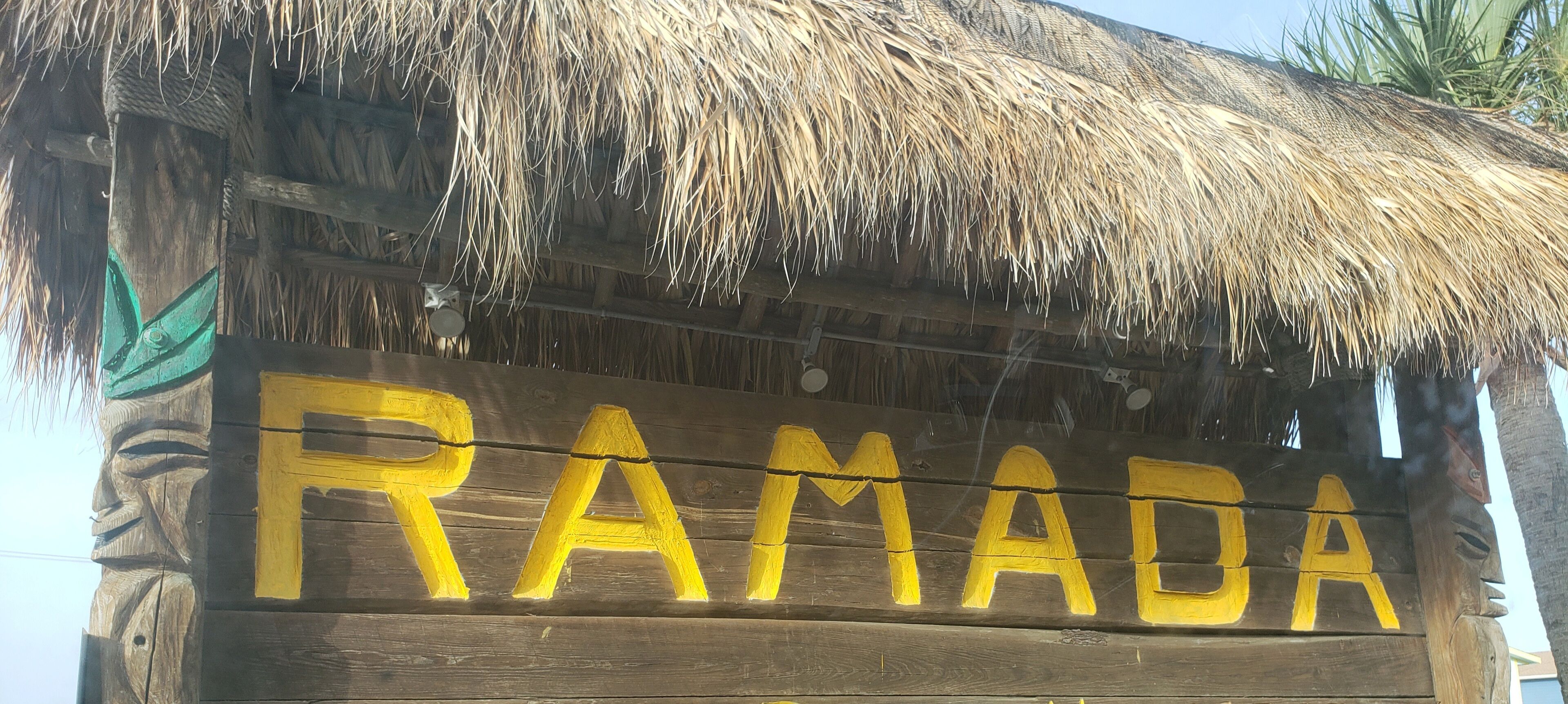 A wooden sign with the word "RAMADA" painted in yellow.