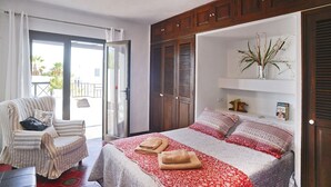 Ein Schlafzimmer mit Bett, Stuhl, Kleiderschrank und Blick durch eine Glastür.