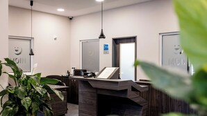 A reception desk with a digital screen, a plant, and a sign indicating a 24-hour service. - Hotel Kiel-Schwedenkai (Kiel)