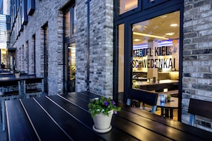 A brick building with a restaurant visible through the window, featuring a sign that reads 'HOTEL KIEL SCHWEDENKAI'.