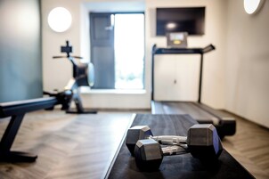 Un gimnasio con equipo de ejercicio, una cinta de correr y un televisor en la pared.
