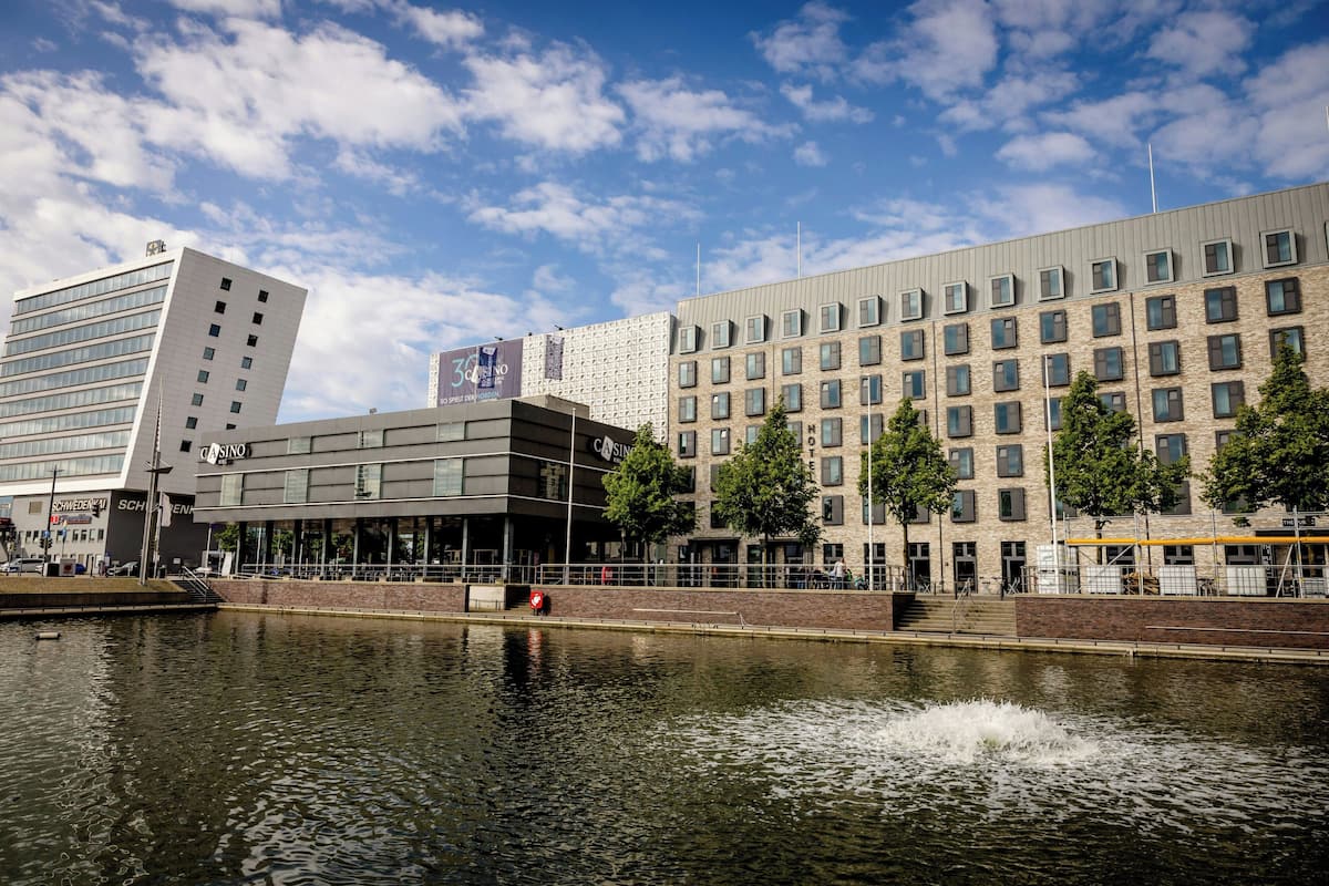 A modern building with a casino, a river in front, and a clear sky.