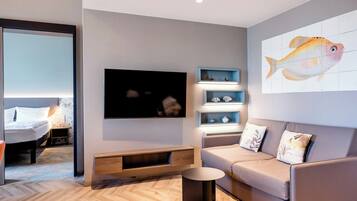 Una sala de estar moderna con un sofá, un televisor, una mesa de centro y una estantería de pared con objetos decorativos.