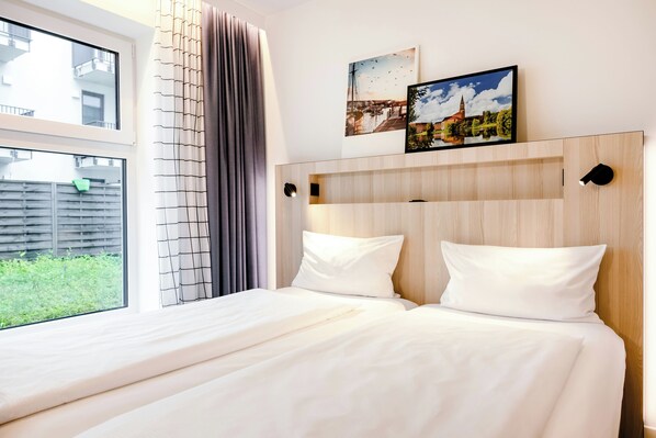Una habitación de hotel con una cama grande, una ventana con cortinas y una obra de arte en la pared.