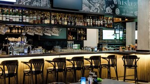 A bar area with multiple liquor bottles, glasses, and a coffee machine. - Hotel Kiel-Schwedenkai (Kiel)
