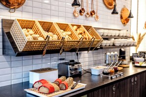 A breakfast buffet with bread, pastries, and beverages.