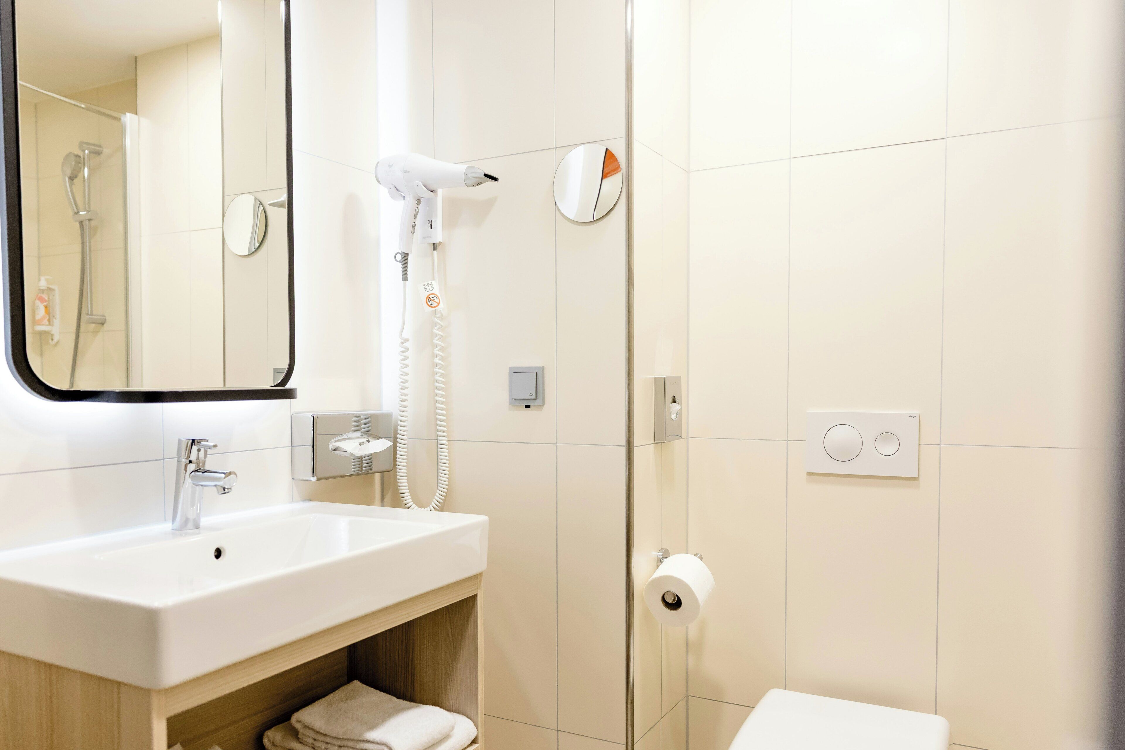 Ein modernes Badezimmer mit Waschbecken, Spiegel, Dusche und Toilette.