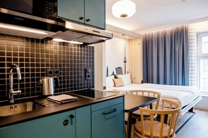 Una habitación de hotel moderna con kitchenette, cama con vistas y zona de comedor.