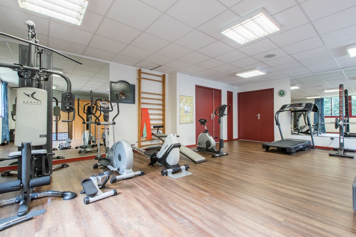 A gym with various exercise equipment, including treadmills, stationary bikes, and weight machines.