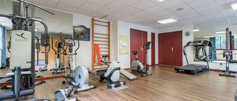 A gym with various exercise equipment, including treadmills, stationary bikes, and weight machines.