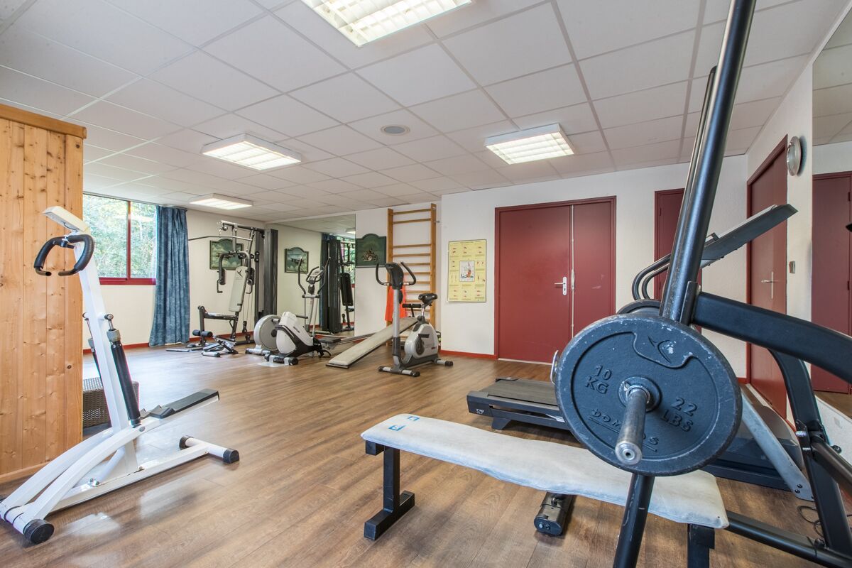 Een sportschool met diverse fitnessapparaten, waaronder loopbanden, krachtapparaten en gewichten.