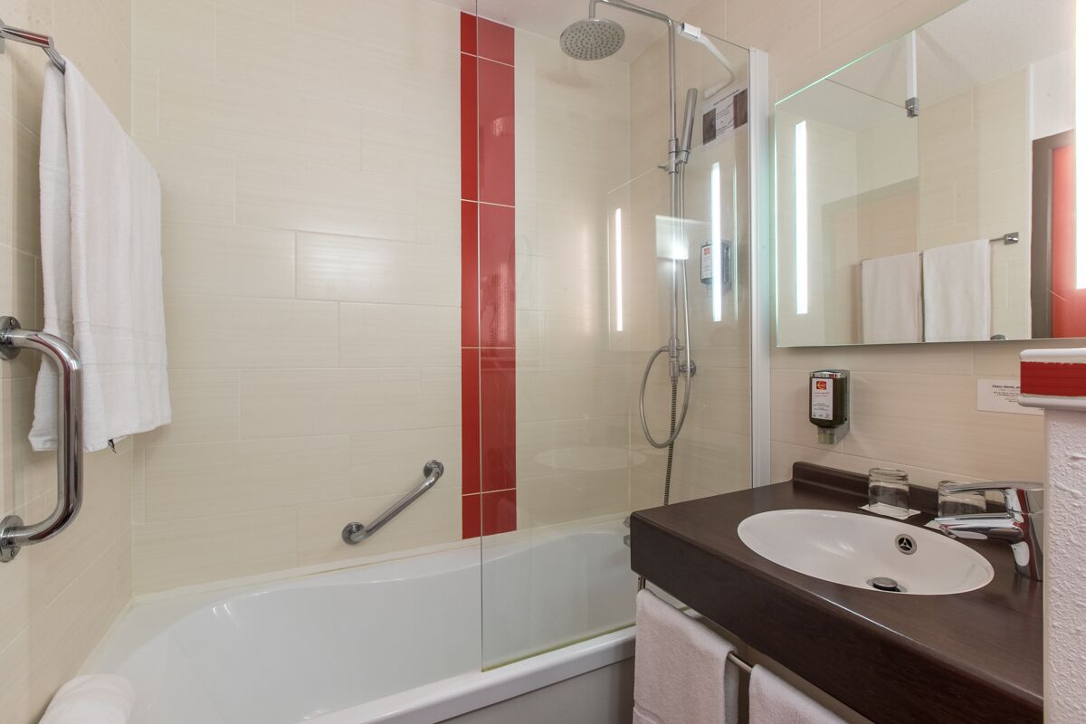 Ein modernes Badezimmer mit Badewanne, Dusche, Waschbecken und einem großen Spiegel.