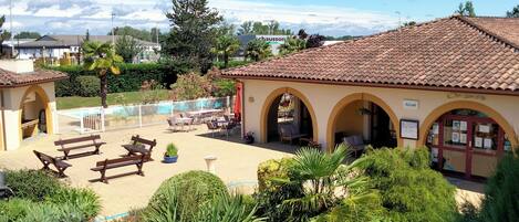 A courtyard with outdoor seating, a pool, and a building with arches.