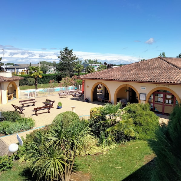 A courtyard with outdoor seating, a pool, and a building with arches.