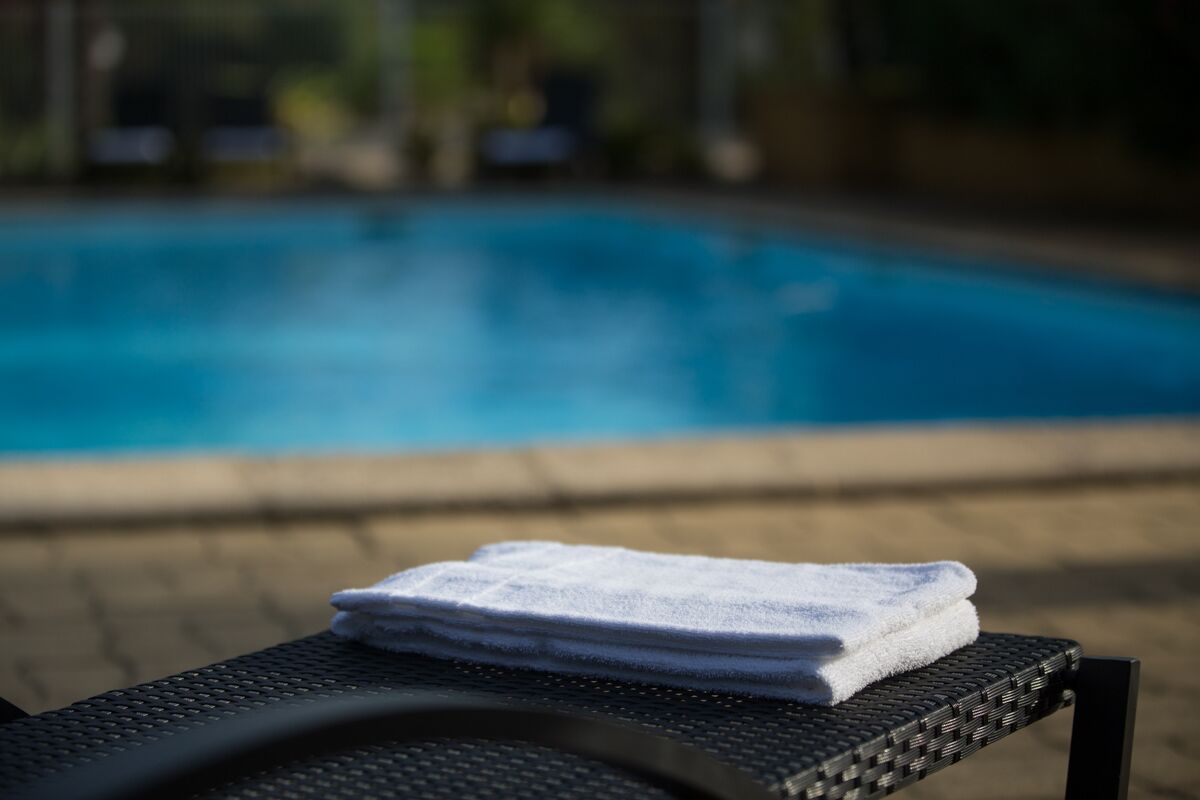 A poolside area with a chair and a folded towel.