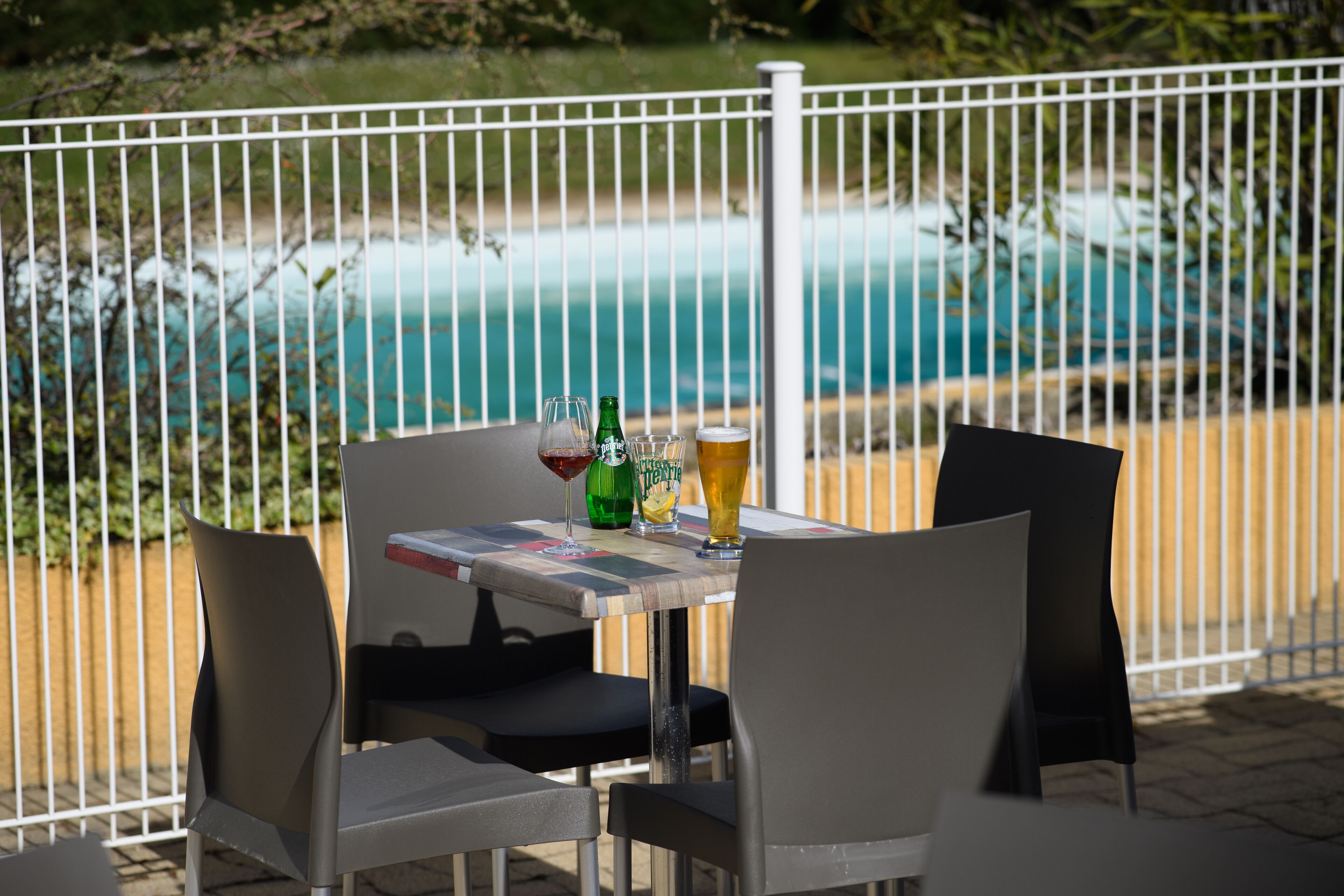 A table with chairs and drinks, overlooking a pool.