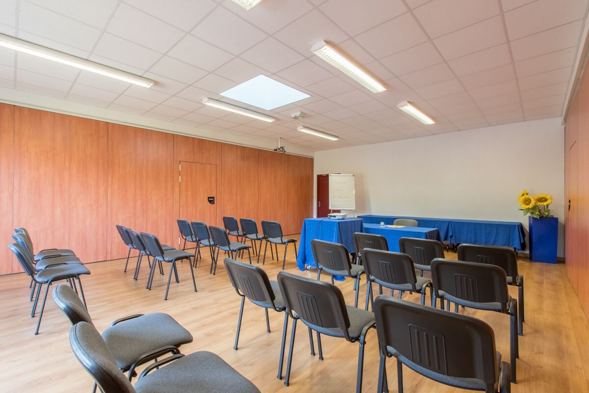 A conference room with rows of chairs, a whiteboard, and a table with a blue tablecloth.