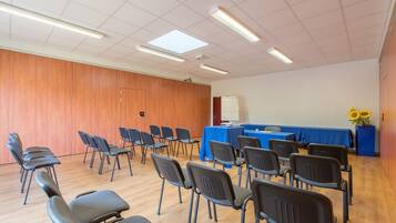 A conference room with rows of chairs, a whiteboard, and a table with a blue tablecloth.