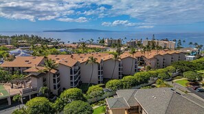 A coastal hotel complex with multiple buildings, some with solar panels, and a view of the ocean. - Beachfront 1BR ocean view condo with pool and hot tub summer deals (Kihei)