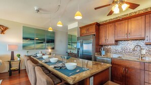 Una cocina moderna con armarios de madera, un refrigerador de acero inoxidable y una encimera de granito.