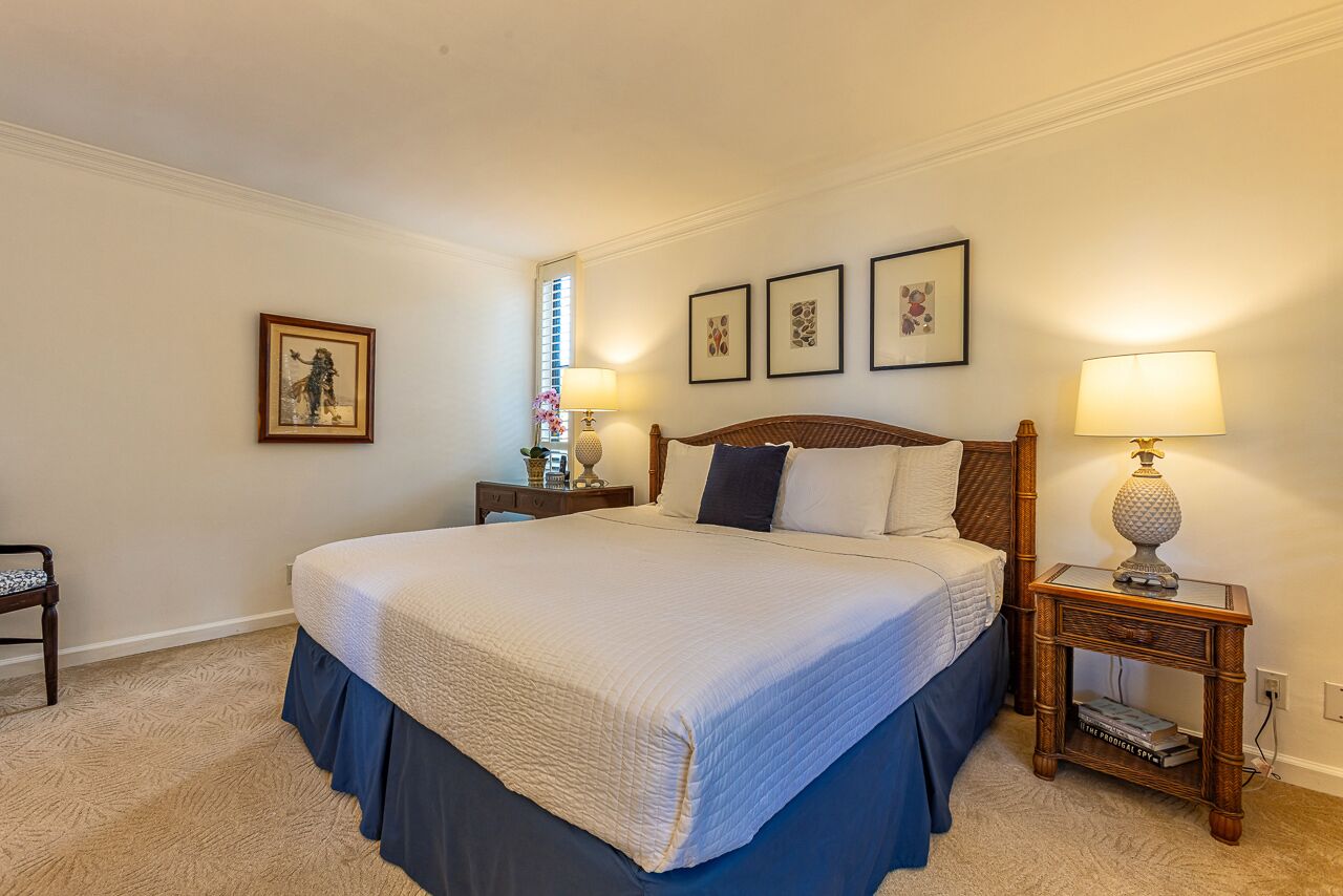 A neatly arranged bedroom with a large bed, two bedside tables, and framed artwork on the wall.