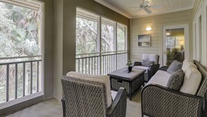 A covered patio with wicker furniture, large windows, and a ceiling fan. - 8126 Wendover Dunes - Palmetto Dunes Oceanside Community (Hilton Head Island)