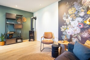 Una sala de estar moderna con un sofá, una silla, una estantería y un detalle decorativo en la pared.