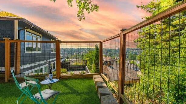 A patio with a view of a cityscape, a small table with chairs, and a wooden fence. - Fremont Bungalow with Backyard View Seattle (Seattle)