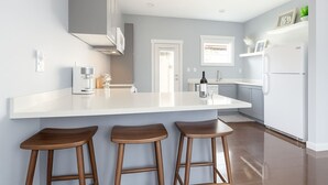 A modern kitchen with a large island, bar stools, and a refrigerator. - Fremont Bungalow with Backyard View Seattle (Seattle)