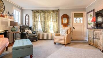 A living room with a fireplace, a sofa, a chair, and a large window with curtains.