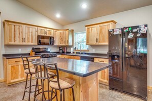 Una cocina moderna con armarios de madera, un refrigerador de acero inoxidable y una isla central con taburetes de bar.
