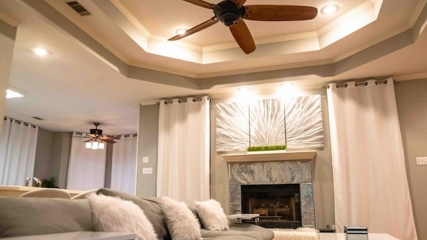 A living room with a sofa, a fireplace, and a ceiling fan.