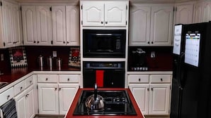 A kitchen with white cabinets, a black microwave, a stove, and a refrigerator.