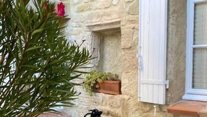 A stone-walled outdoor dining area with wicker chairs, a table set with a coffee pot, bowls, and a glass of orange juice. - Grand Luxe SENSATION Suite with private Jacuzzi (Martignargues)