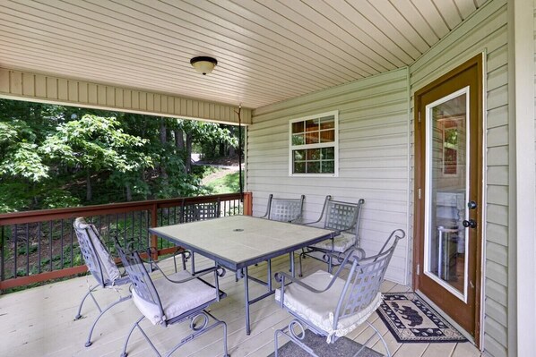 A covered porch with a table and chairs, a door with a glass panel, and a view of trees. - Respite Ridge - Game Room-Fireplace-Stunning View (Young Harris)
