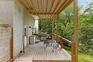 Une terrasse en bois avec un barbecue et un espace salon extérieur.