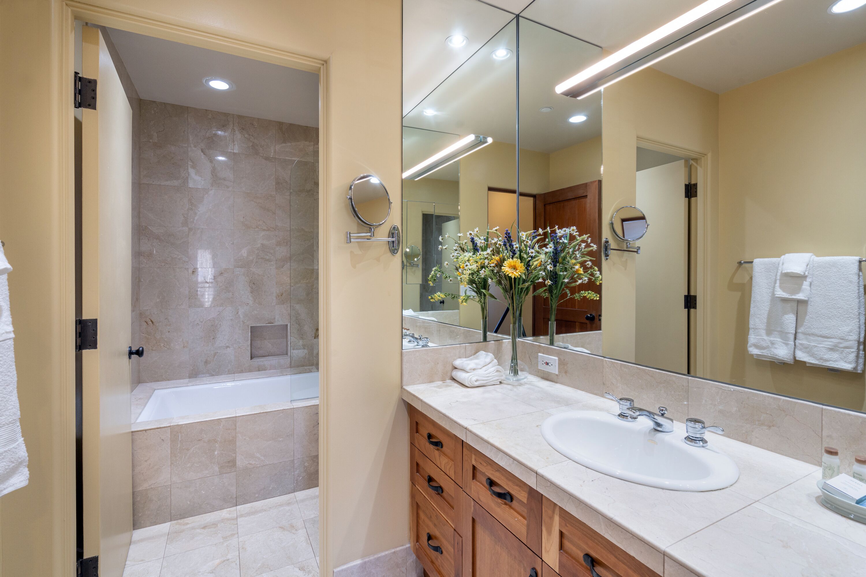 A modern bathroom with a bathtub, a sink, and a large mirror.