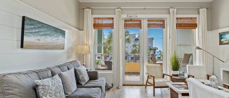 A living room with a grey sofa, a coffee table, and a view of the outside balcony.