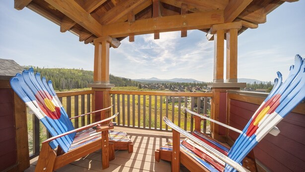 A wooden deck with two Adirondack chairs, a wooden pergola, and a view of a forested mountain range. - Cozens Pointe B-301 3 Bedroom Condo by RedAwning (Fraser)