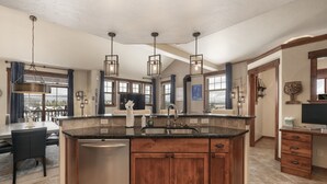 A spacious kitchen with a central island, stainless steel dishwasher, wooden cabinets, and pendant lighting. - Cozens Pointe B-301 3 Bedroom Condo by RedAwning (Fraser)