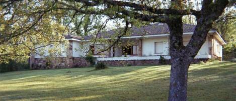 A house with a sloped roof, a stone foundation, and a well-maintained lawn.