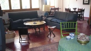 Un salon avec un canapé, une table basse, une petite table sur laquelle sont posés des bols, et un fauteuil vert.